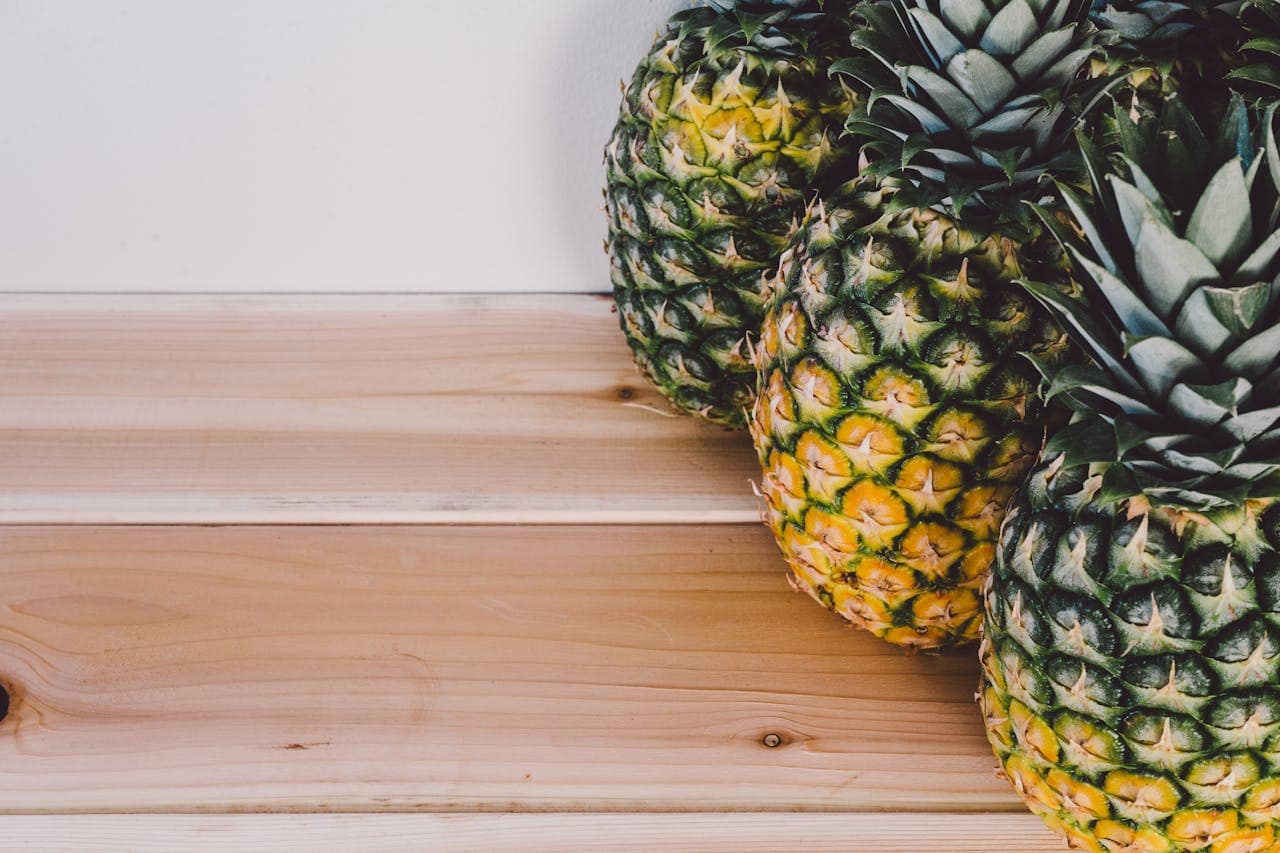 Close-up of fresh pineapples on a wooden table, showcasing tropical fruit textures.
