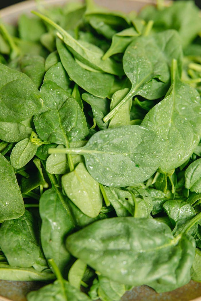 Vibrant green spinach leaves covered in refreshing water droplets, showcasing freshness and health.